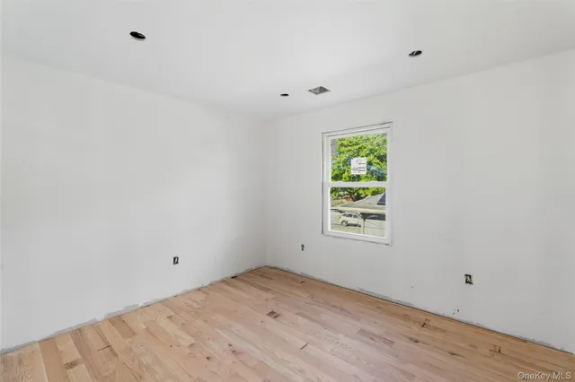 a view of an empty room with wooden floor and window