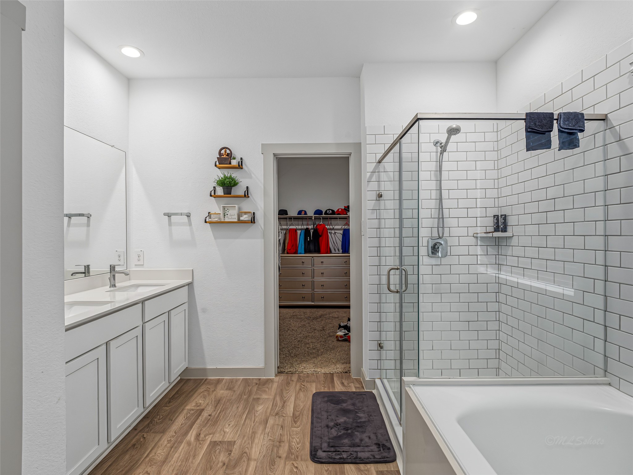 8043 Milam Lane Rosharon, TX 77583 - Photo 20 of 41 Prepare to indulge in your own private spa-like haven! This primary ensuite bathroom is a masterclass in modern luxury, featuring an expansive layout anchored by beautiful, durable wood-look flooring and crisp white finishes.