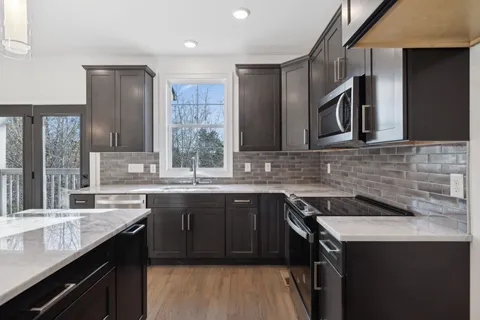 a kitchen with stainless steel appliances granite countertop a sink stove and cabinets