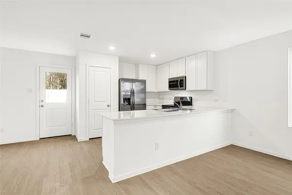 a view of kitchen with stainless steel appliances granite countertop a stove a sink dishwasher and a refrigerator with wooden floor