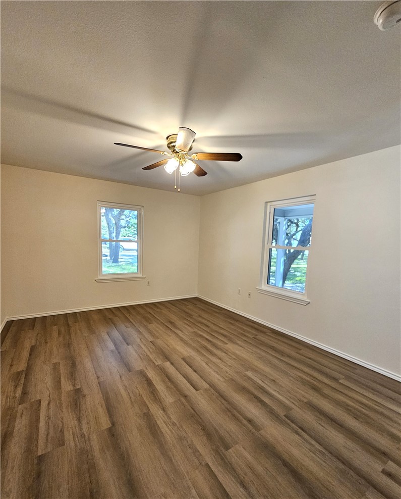 3121 Lenore Avenue Ingleside, TX 78362 - Photo 14 of 24 an empty room with wooden floor chandelier fan and windows