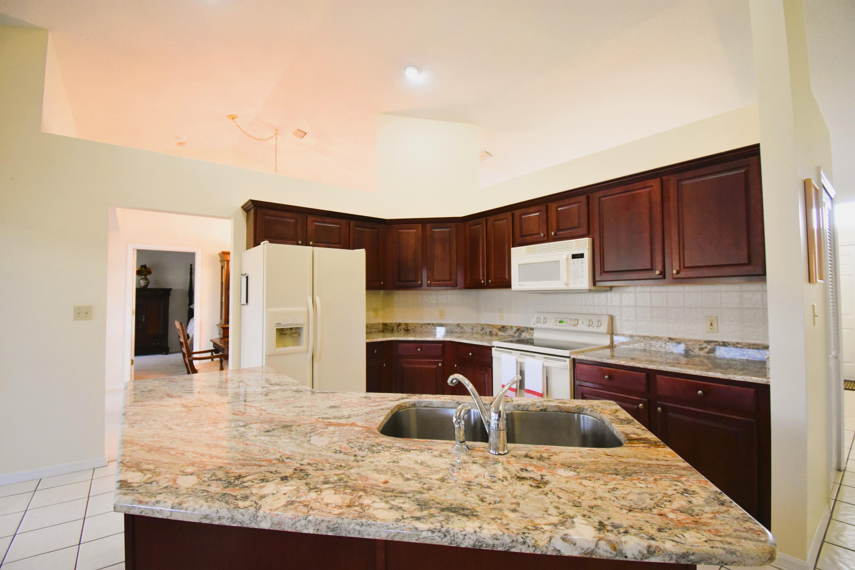 1920 Glen Meadows Circle Melbourne, FL 32935 - Photo 10 of 19 a kitchen with kitchen island granite countertop a refrigerator and a stove top oven