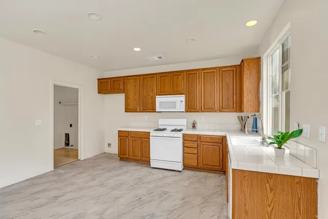 a view of a kitchen with stainless steel appliances granite countertop a sink and a window