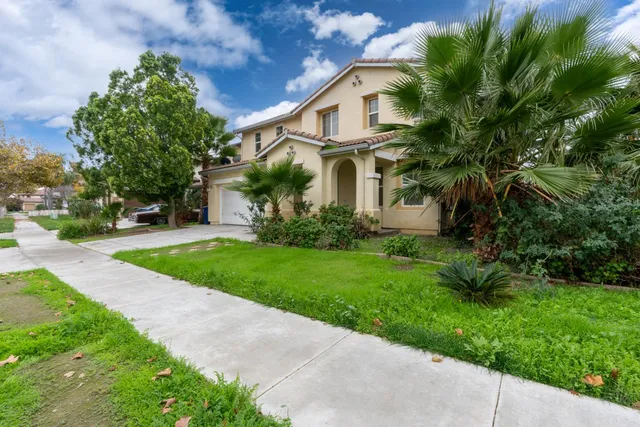 a view of a white house next to a yard with big trees