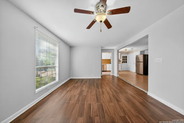 a view of empty room with wooden floor and fan