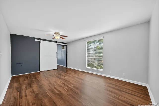 a view of an empty room with wooden floor and a window