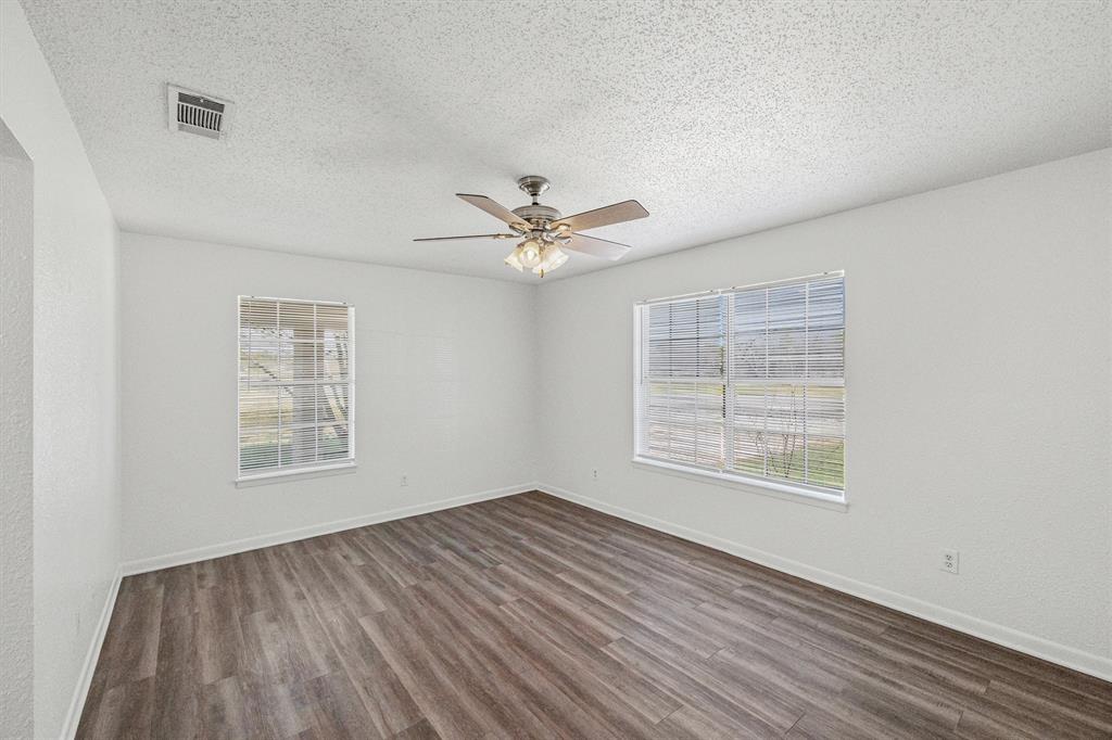 500 Highway 22 Meridian, TX 76665 - Photo 5 of 28 an empty room with wooden floor chandelier fan and windows
