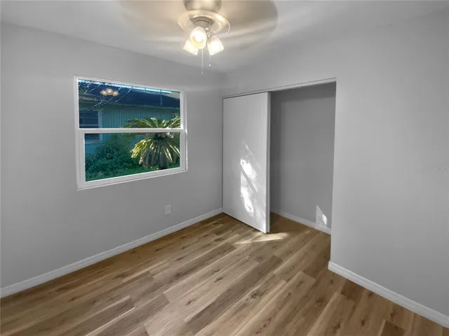 a view of an empty room with window and wooden floor