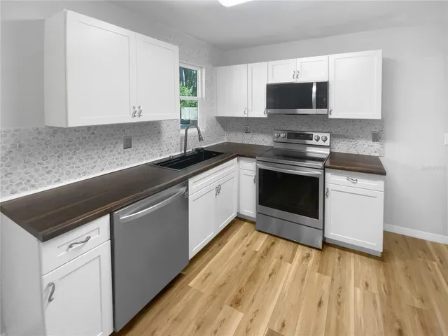 a kitchen with stainless steel appliances granite countertop a sink and cabinets with wooden floor