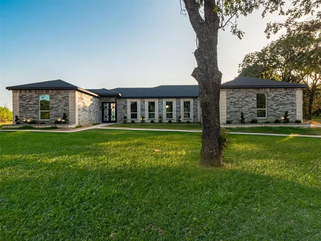 a view of a house with a big yard and large trees