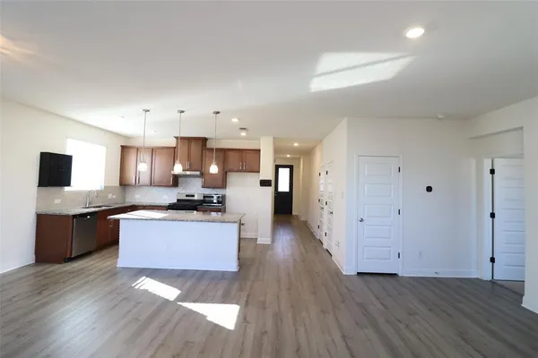 a large kitchen with a center island wooden floor and stainless steel appliances