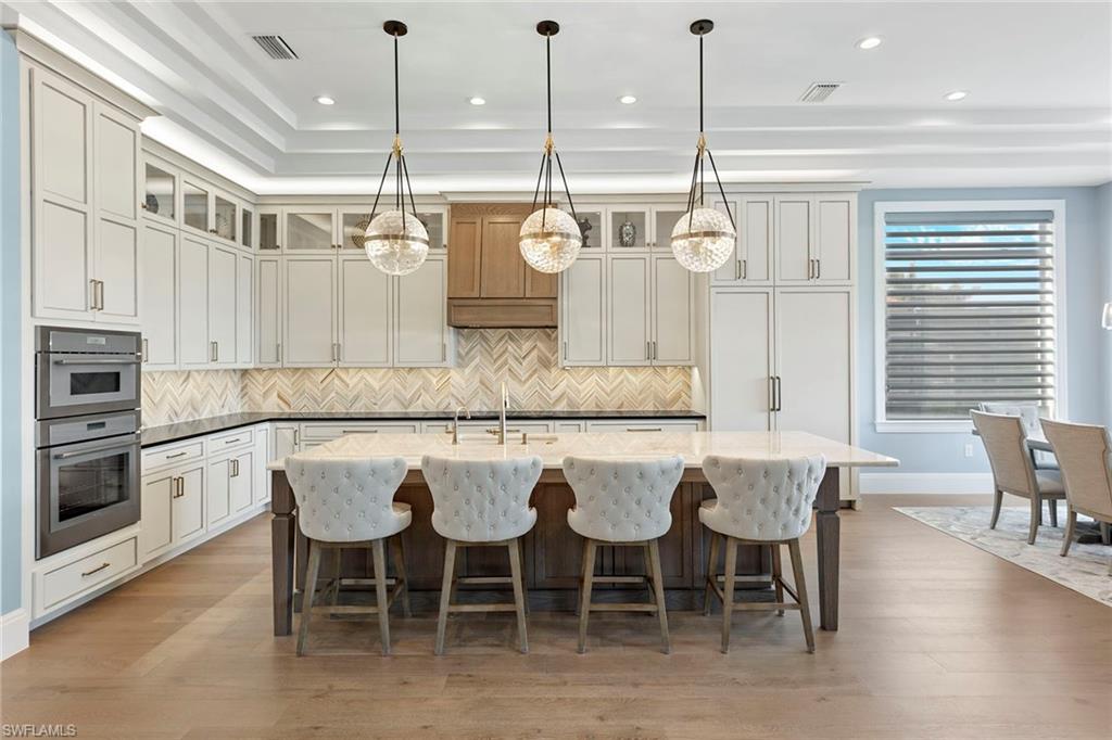 a kitchen with stainless steel appliances granite countertop a dining table chairs and white cabinets