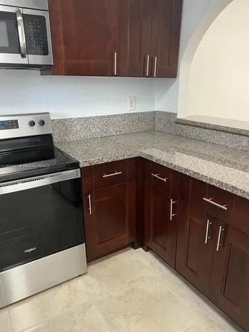 a kitchen with granite countertop cabinets stove and microwave