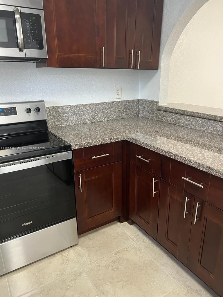 2670 West 76th Street, Unit 101 Hialeah, FL 33016 - Photo 10 of 35 a kitchen with granite countertop cabinets stove and microwave