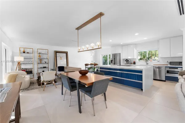 a kitchen with stainless steel appliances kitchen island granite countertop a table chairs and a refrigerator