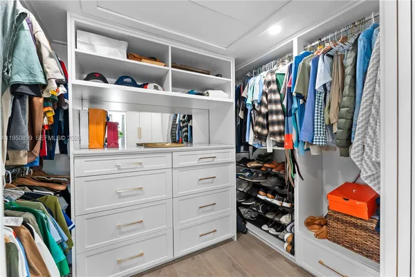 a view of walk in closet with clothes and shoes