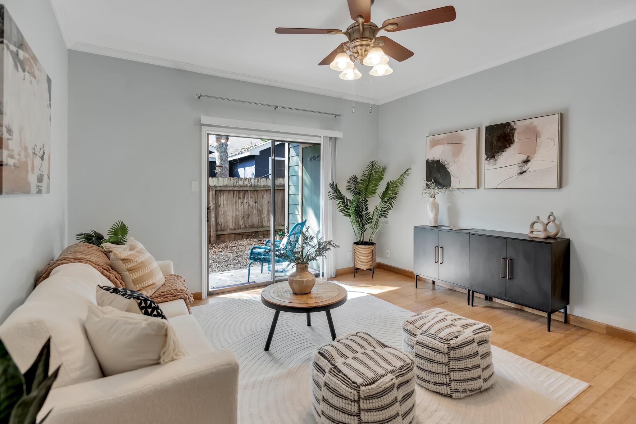 Living area featuring light wood flooring, a ceiling fan, and sliding glass doors that open to a fenced outdoor area