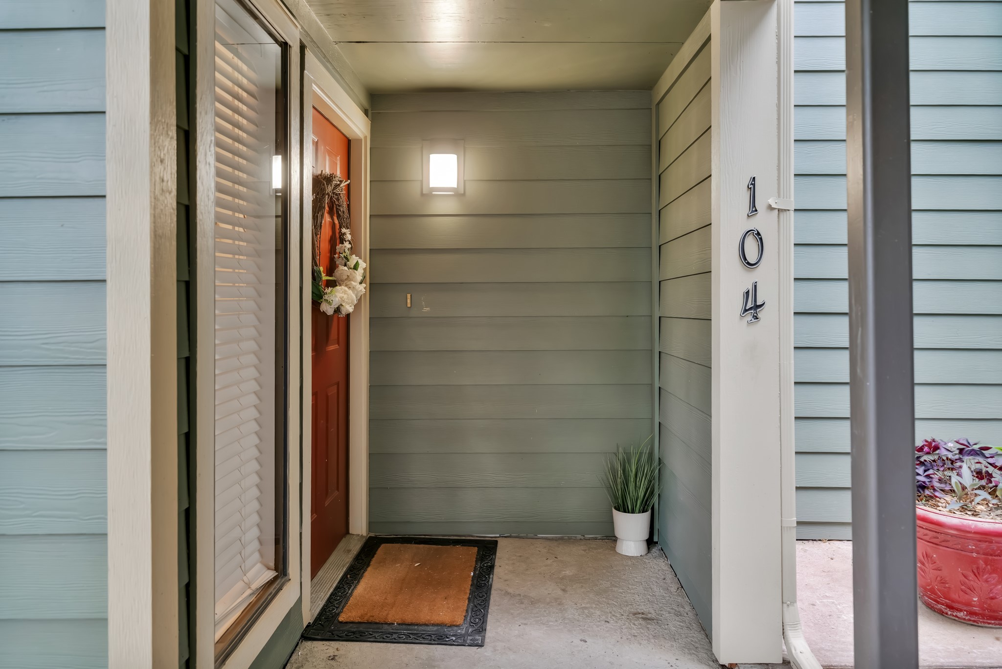 11970 Jollyville Road, Unit 104 Austin, TX 78759 - Photo 19 of 22 Inviting front entry featuring a red door, outdoor wall lighting, and a transom window with blinds