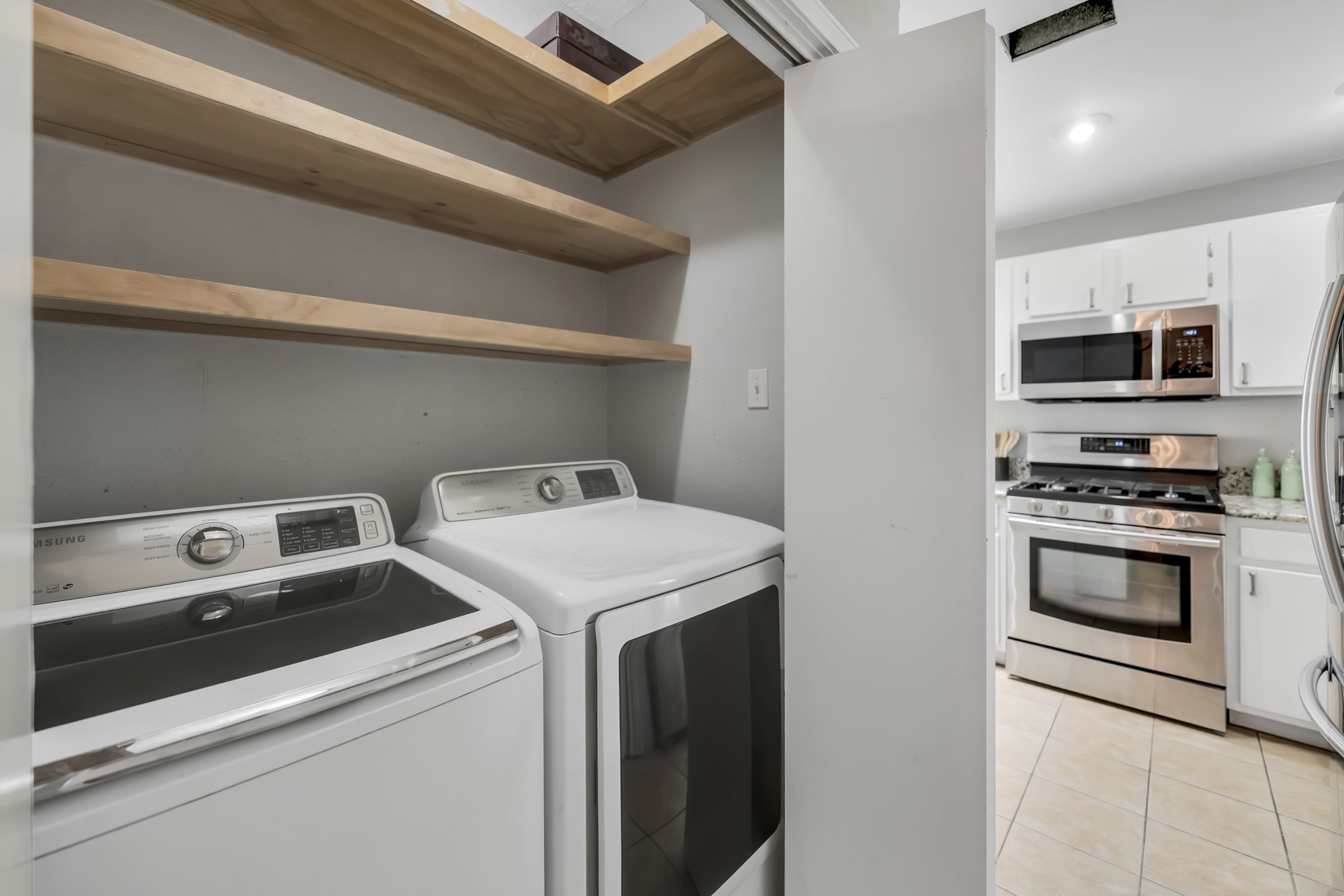 11970 Jollyville Road, Unit 104 Austin, TX 78759 - Photo 8 of 22 Laundry area with two white appliances and three wooden shelves