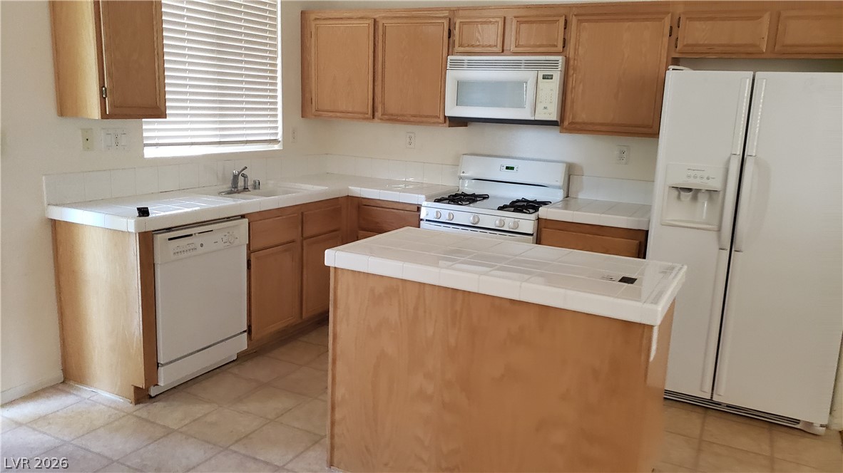 9112 Manalang Road Las Vegas, NV 89123 - Photo 31 of 50 A functional kitchen features an island, ample cabinetry, and white tile countertops.