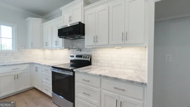 a kitchen with granite countertop white cabinets and black appliances