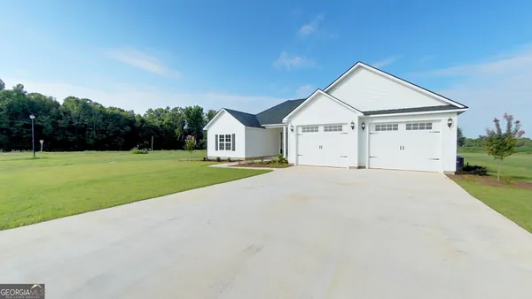 a view of white house with a big yard and large trees