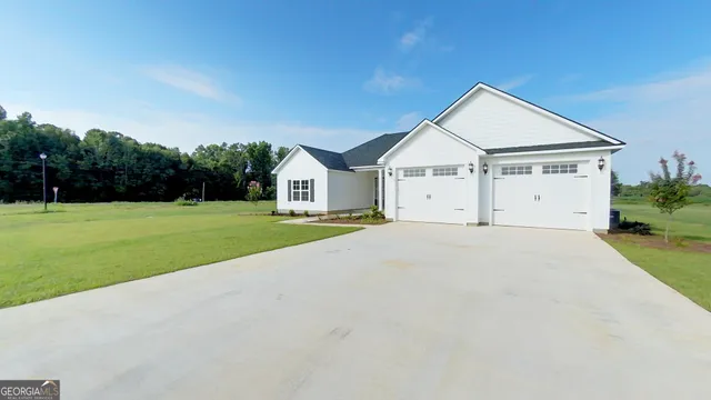 a view of white house with a big yard and large trees