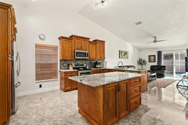 a kitchen with stainless steel appliances granite countertop a stove top oven a sink a dining table and chairs