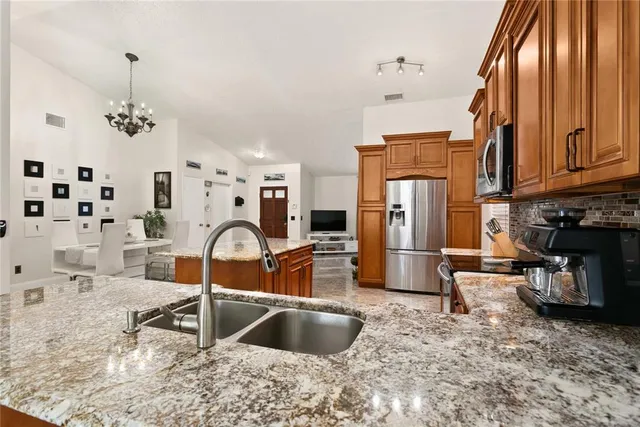 a kitchen with stainless steel appliances granite countertop a sink refrigerator and cabinets