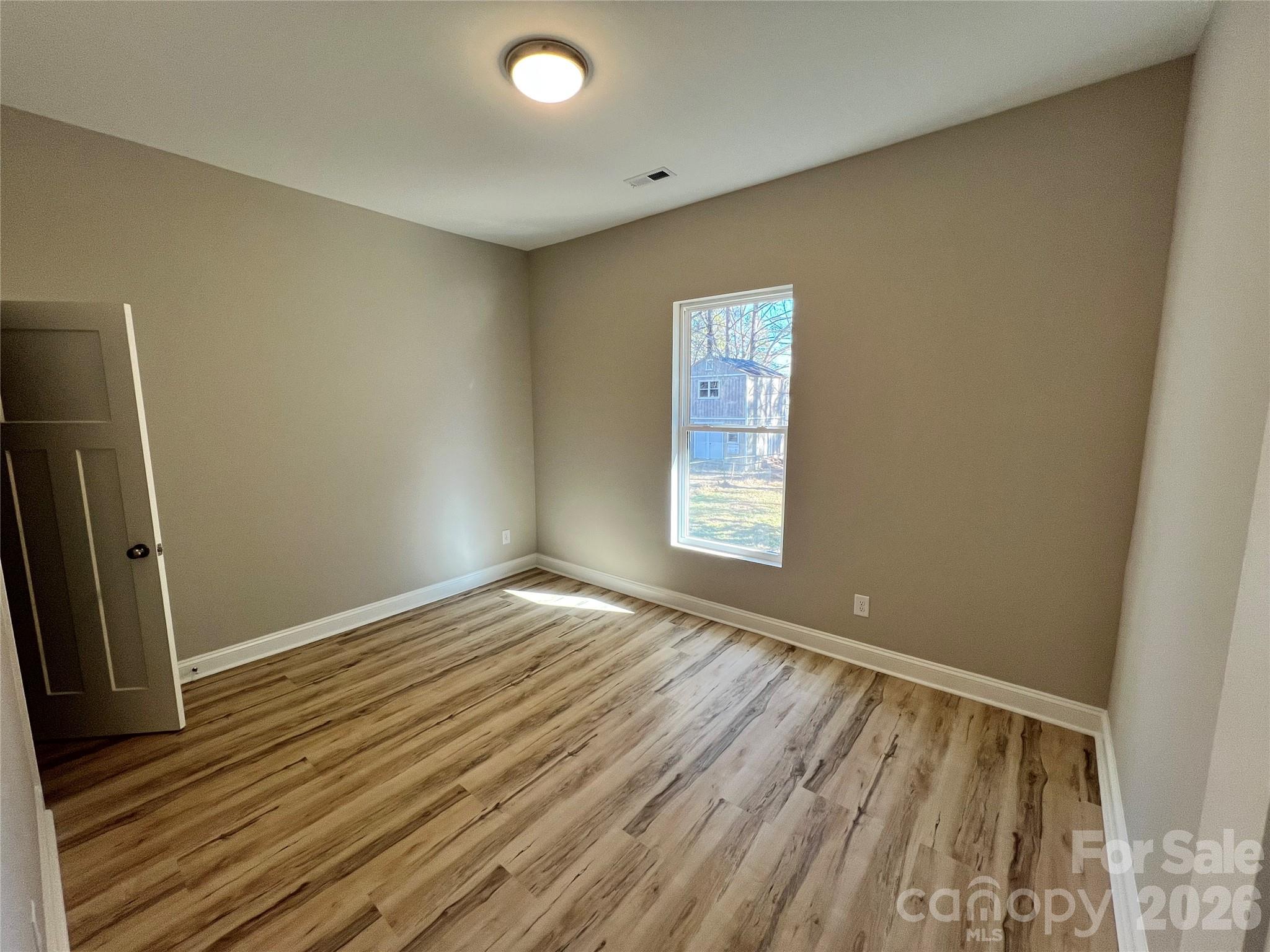 722 Austin Street Albemarle, NC 28001 - Photo 18 of 22 an empty room with wooden floor and windows