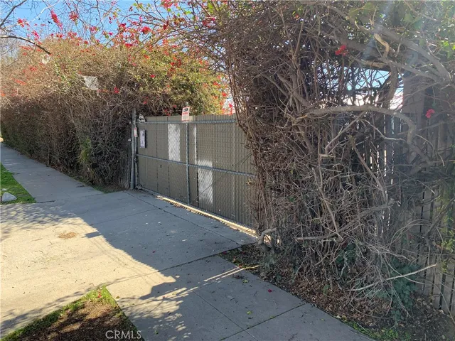 a backyard of a house with large trees and wooden fence