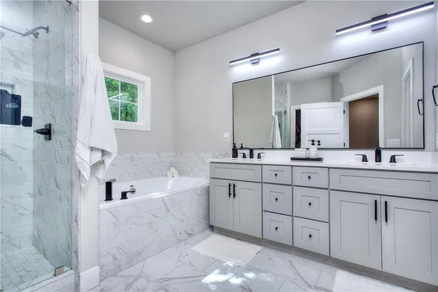 a spacious bathroom with double vanity a mirror a bathtub and a sink