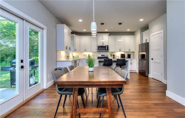 a kitchen with a table chairs refrigerator and wooden floor