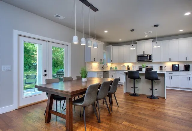 a kitchen with stainless steel appliances kitchen island granite countertop a table chairs and a wooden cabinets
