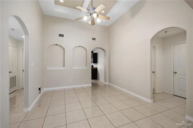 a view of an empty room with window and chandelier fan