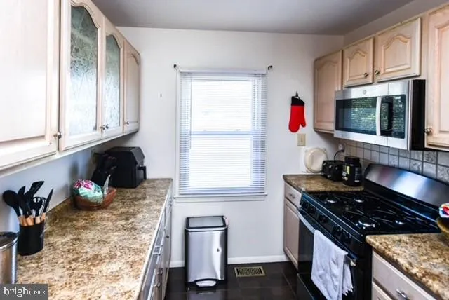 a kitchen with granite countertop a stove a sink and dishwasher wooden cabinets with wooden floor