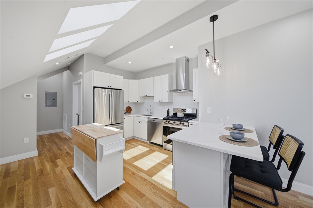 174 Walnut Street, Unit 3 Somerville, MA 02145 - Photo 6 of 38 a living room with stainless steel appliances kitchen island a table chairs and a refrigerator
