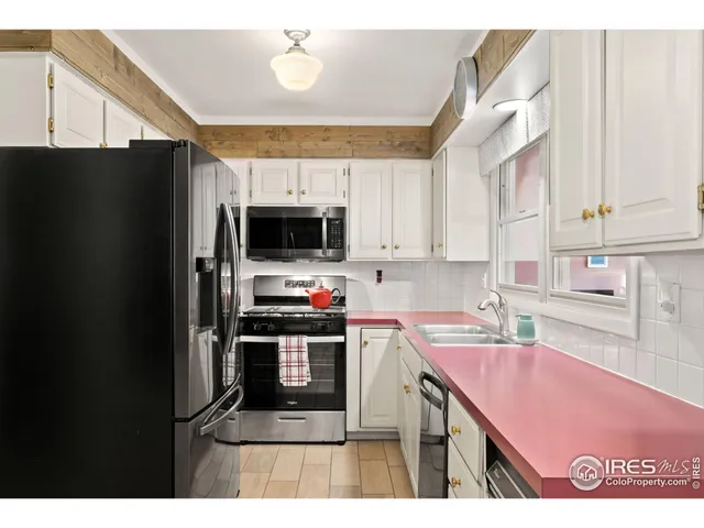 a kitchen with stainless steel appliances a sink a microwave a refrigerator and cabinets