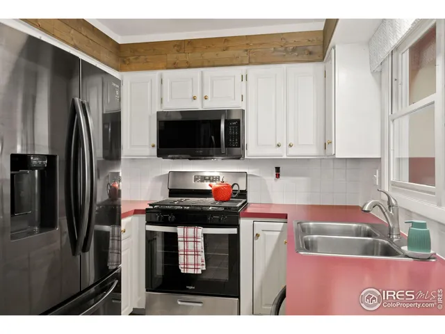 a kitchen with stainless steel appliances a stove a refrigerator a sink and white cabinets