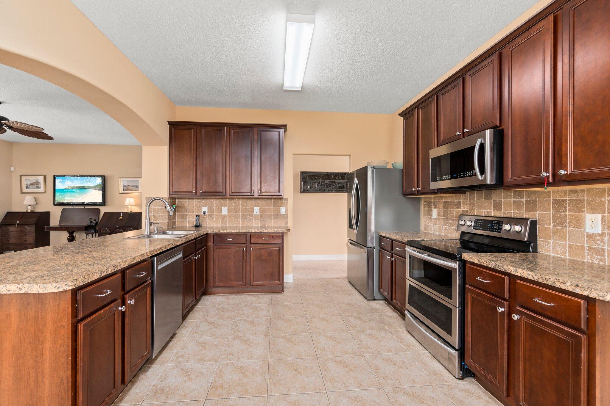 2309 Southwest Ivory Road Port St. Lucie, FL 34953 - Photo 9 of 46 a kitchen with stainless steel appliances granite countertop wooden cabinets a stove top oven a sink and dishwasher