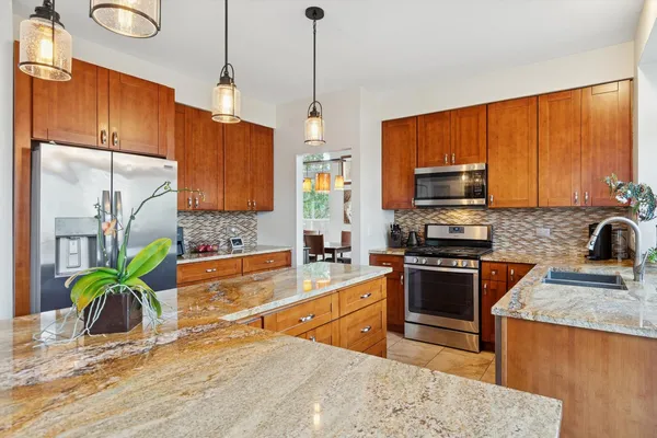 a kitchen with stainless steel appliances granite countertop a stove a sink a refrigerator a stove a dining table and chairs with wooden floor