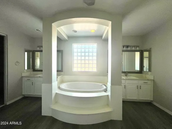 a spacious bathroom with a double vanity sink a mirror and a bathtub