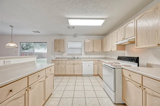 an empty room with chandelier fan and windows