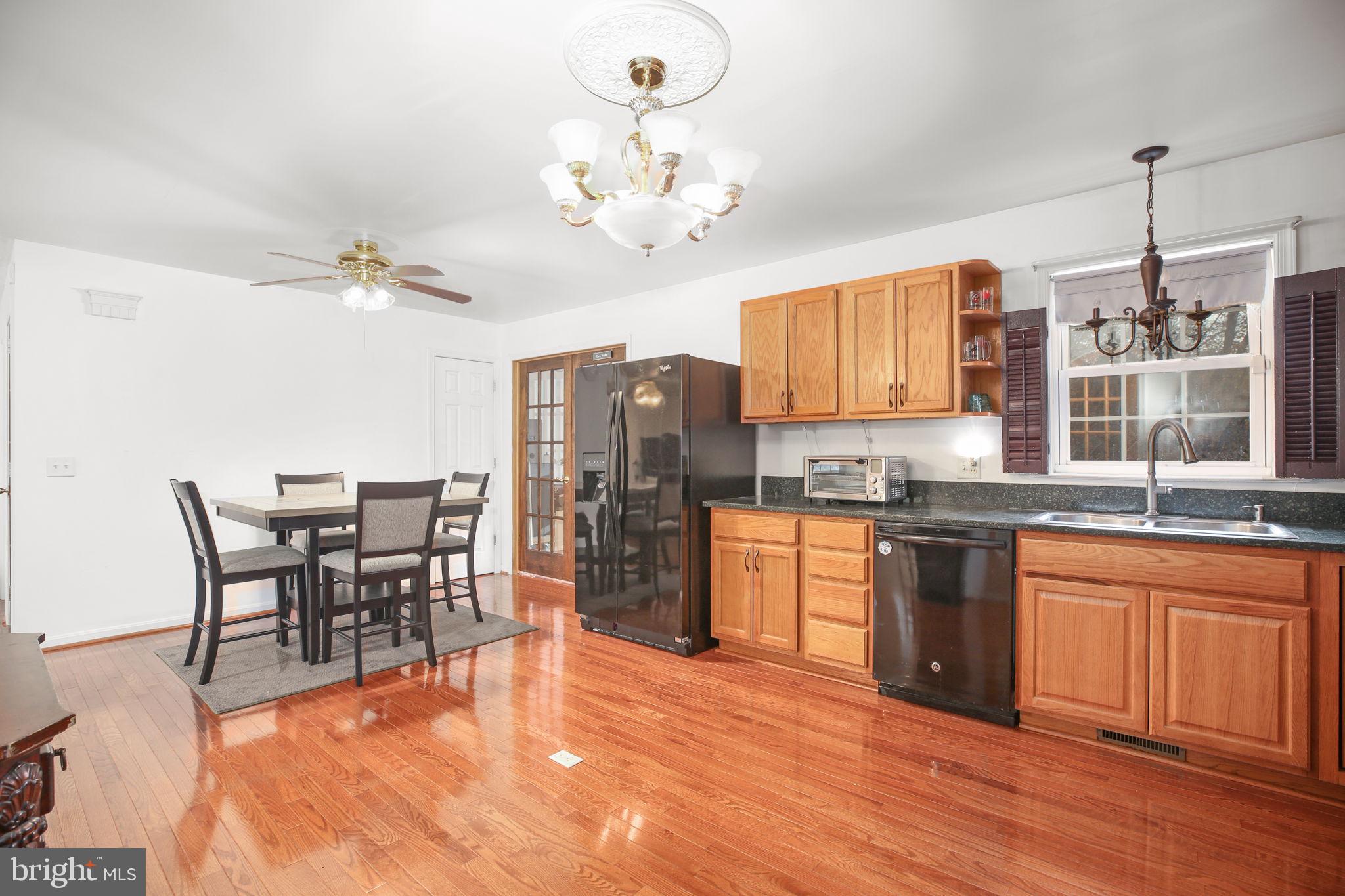 315 Sandy Ridge Road Fredericksburg, VA 22405 - Photo 6 of 42 a open kitchen with stainless steel appliances granite countertop a stove top oven a sink a dining table and chairs with wooden floor