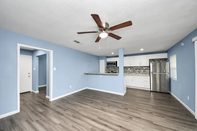 a view of empty room with wooden floor and ceiling fan