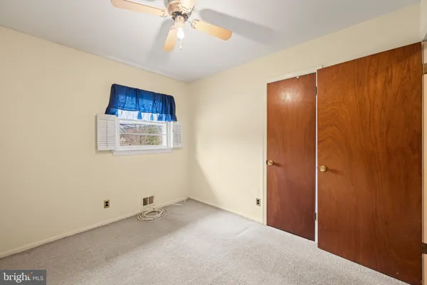an empty room with a ceiling fan and window
