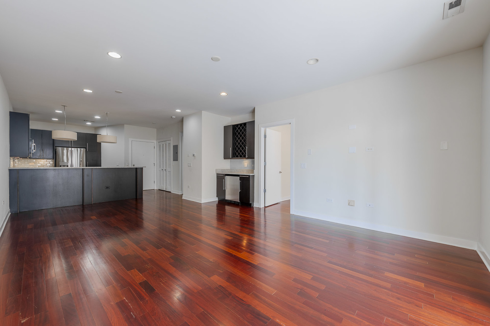 1162 West Hubbard Street, Unit 203 Chicago, IL 60642 - Photo 5 of 22 a view of an empty room with wooden floor and a kitchen