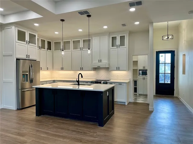 a large kitchen with stainless steel appliances granite countertop a lot of counter space and wooden floor