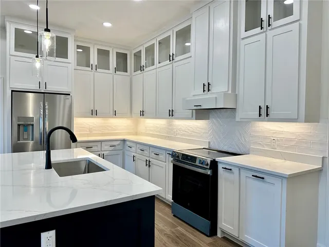 a kitchen with stainless steel appliances granite countertop a sink stove and refrigerator