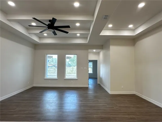 an empty room with wooden floor fan and windows